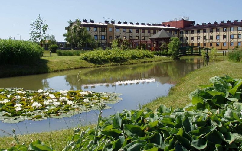 Zdjęcie przedstawia hotel 500 w Tarnowie Podgórnym obok którego znajduje się staw