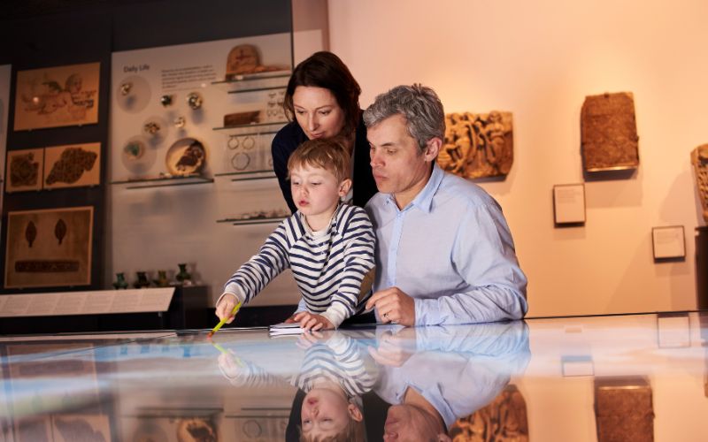 Zdjęcie przedstawia rodziców z dzieckiem, którzy zwiedzają muzeum