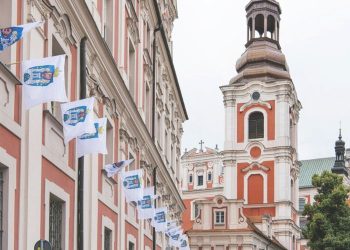 Zdjęcie przedstawia wywieszone flagi na budynku z herbem miasta Poznań