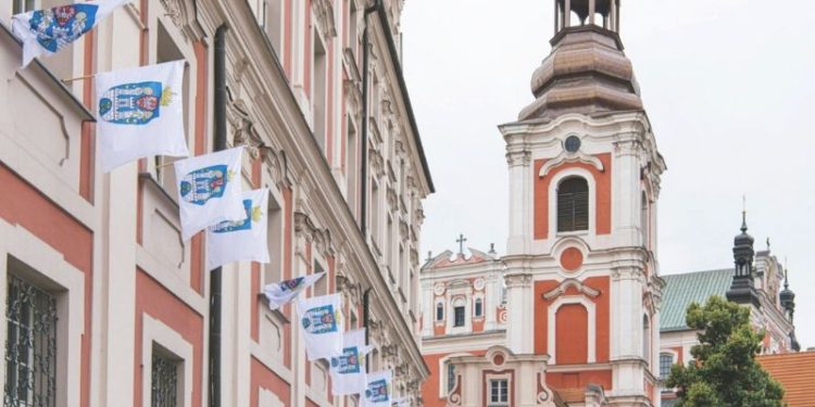 Zdjęcie przedstawia wywieszone flagi na budynku z herbem miasta Poznań