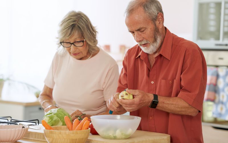 Zdjęcie przedstawia parę emrerytów, którzy wspólnie gotują