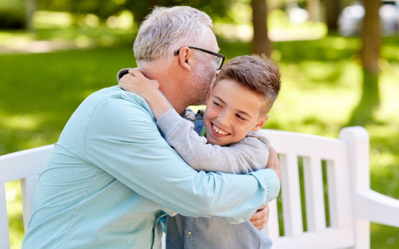 Zdjęcie przedstawia mężczyznę i chłopczyka, którzy się przytulają