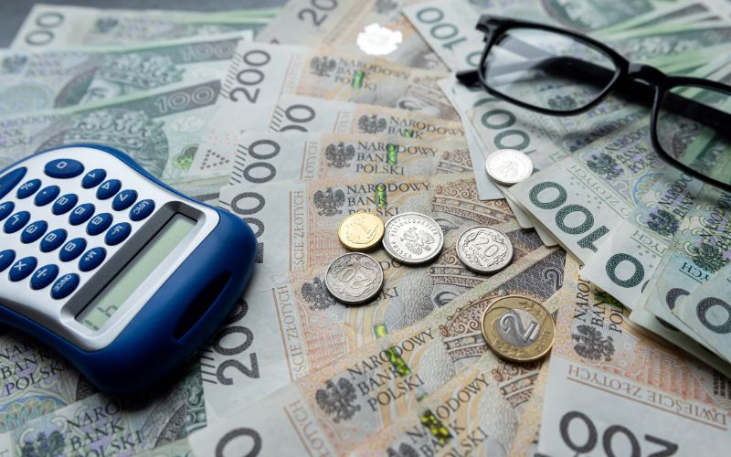 Zdjęcie przedstawia pieniądze PLN z kalkulatorem na stole