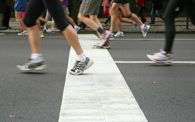 Zdjęcie przedstawia nogi osób, które przekraczają linię biegową