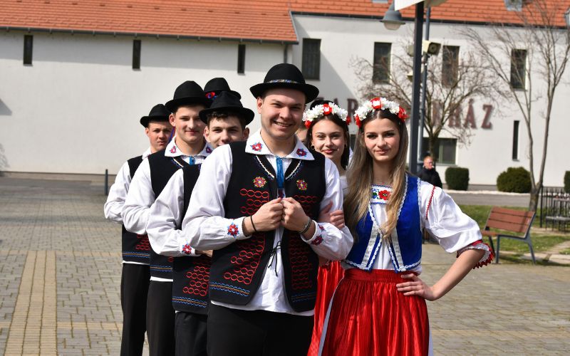 Zdjęcie przedstawia pary osób ubrane w strój ludowy, które przygotowują się do tańczenia poloneza