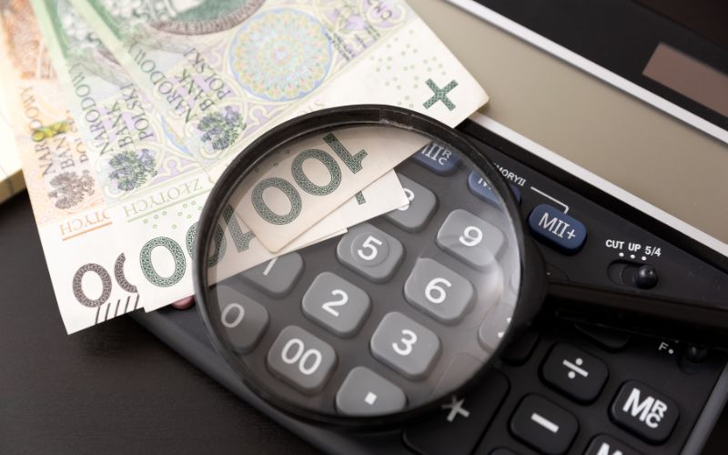 Zdjęcie przedstawia banknoty polskie obok których leży lupa