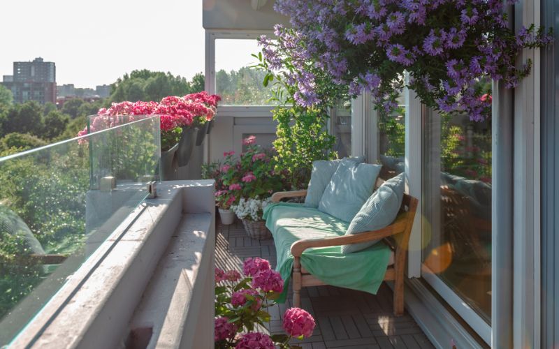 Zdjęcie przedstawia balkon z dużą ilością roślin