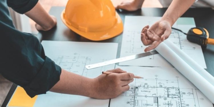 Inżynierowie omawiają projekty budowlane przy żółtym kasku.